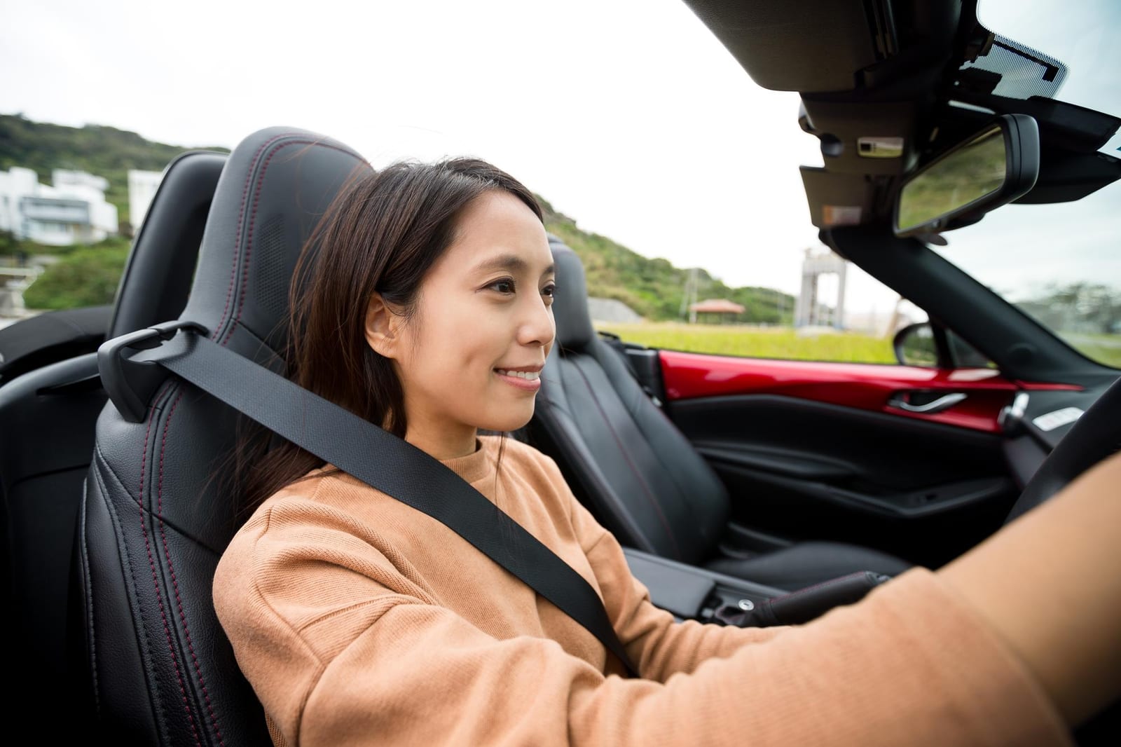 海沿いの道をオープンカーで走る女性